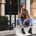 Od ležernog do elegantnog: kako Chelsea čizme upotpunjuju svaki outfit Pretty girl in trench coat and jeans thoughtfully looking aside sitting on little stairs spending time on cozy city street